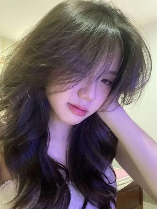 Ánh tím nhẹ phủ lên mái tóc dài của cô gái đang tựa tay, áo sáng màu và biểu cảm trầm tạo cảm giác hình girl xinh thịnh hành