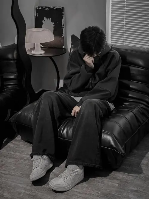 Khung cảnh đơn sắc trắng đen làm tăng sự tò mò về ảnh hot boy giấu mặt mặc áo khoác tối màu ngồi trên ghế sofa da.