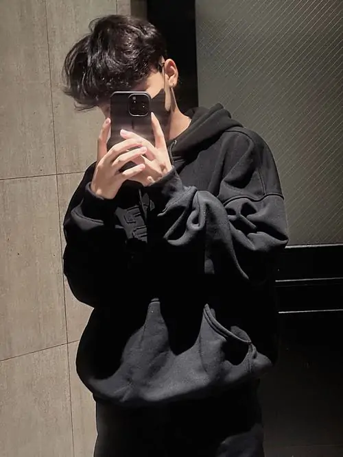 Chiếc gương dọc phản chiếu hình ảnh trai đẹp che mặt mặc áo hoodie đen dày dặn đang đứng tạo dáng vô cùng trẻ trung mộc mạc.