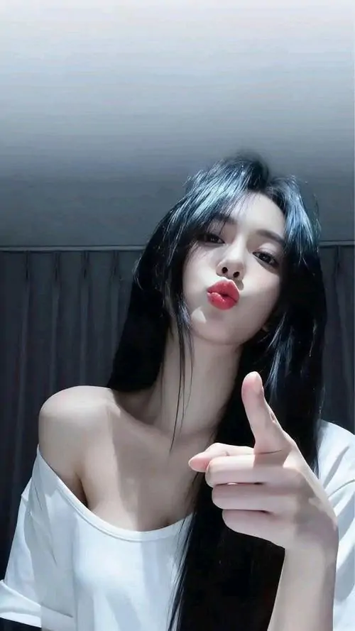 Cô gái tóc dài áo trắng tạo dáng đưa tay về phía máy, màu son đỏ nổi bật trên nền phòng tối có ánh sáng lạnh