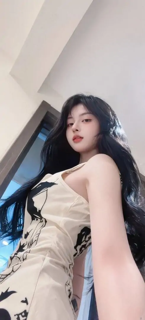 Trước gương, cô gái tóc dài mặc váy trắng ôm nhẹ, dáng đứng nghiêng và màu phòng sáng tạo nét ảnh gái đẹp phây búc