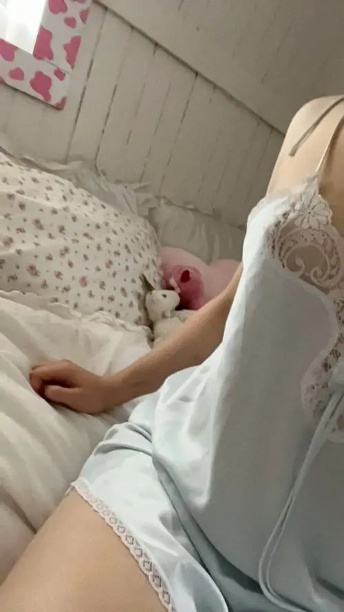 Cô nàng mặc váy trắng nằm nghiêng trên giường hoa nhỏ, mái tóc dài buông xuống gối và dáng pose khá yên bình