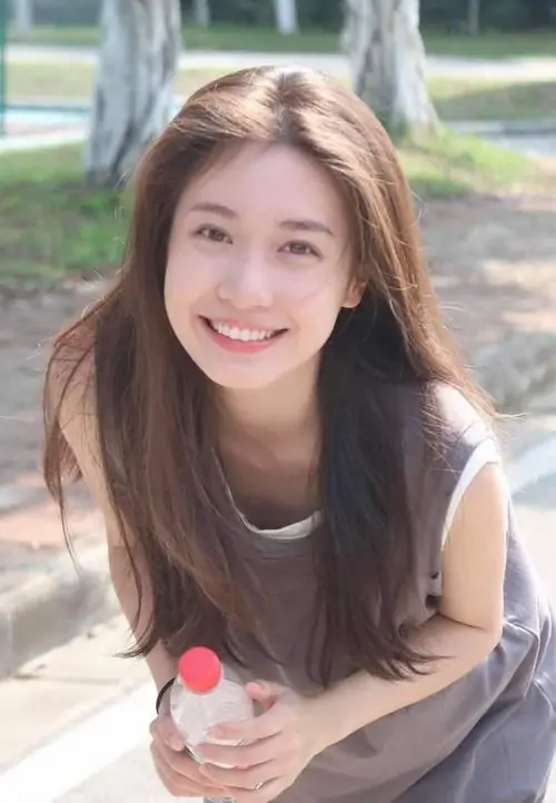 Ánh nắng ngoài công viên phủ lên cô gái áo nâu cầm que kem, mái tóc dài và nụ cười tươi nhìn rất thư thái
