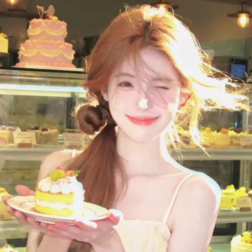Trước tủ bánh ngọt, cô gái áo vàng cầm đĩa bánh cười rạng rỡ, tóc nâu búi lỏng và ánh đèn tạo màu ấm