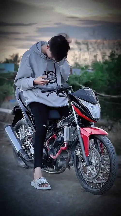 Chiếc khăn len quàng cổ dày màu đỏ đun che khuất phần cằm của chàng trai có làn da trắng đang đứng dưới hàng cây rụng lá mùa thu.
