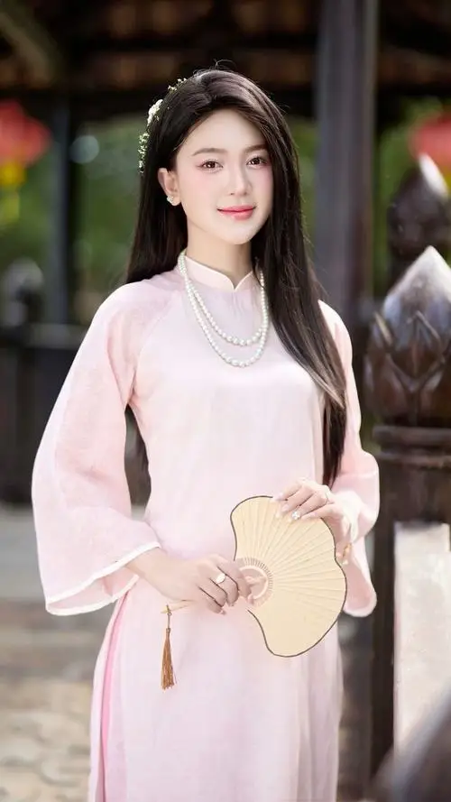 Trong sân đình yên tĩnh, cô gái áo dài vàng nhạt nâng nhẹ tà áo, tạo dáng chụp ảnh áo dài dưới ánh nắng ven