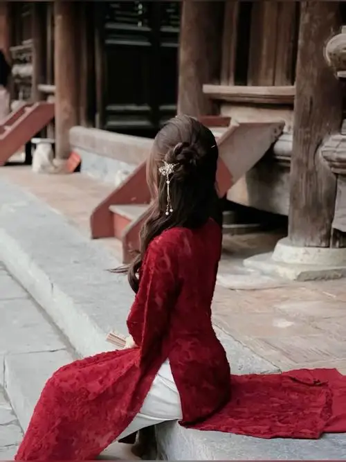 Trên ban công gỗ, cô gái áo dài xanh lam cầm sách nhỏ, dùng tư thế chụp hình áo dài nghiêng người thật tự nhiên