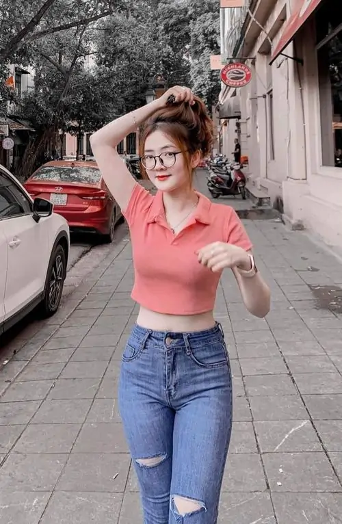 Sân thượng chiều muộn ghi lại cô gái áo khoác bò, jean xanh đồng màu, tóc xõa tự nhiên và tay cầm điện thoại