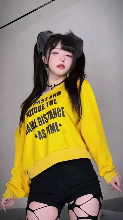 Đèn vàng phía sau làm cô gái mặc đồng phục đen đỏ nổi bật hơn, dáng ngồi xếp bằng và mái tóc dài tạo nét ngây thơ