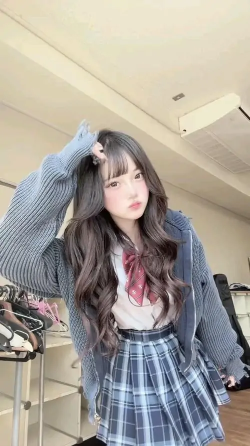Cô gái tóc xoăn nhẹ đặt tay hình trái tim trước ngực, áo nâu mỏng và ánh sáng phòng tắm tạo vibe ảnh gái xinh diễn vũ điệu