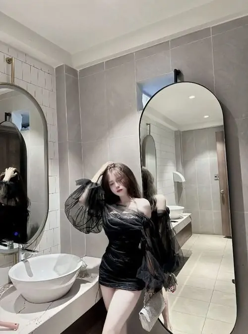 Tà váy ngắn của ảnh người đẹp mặc váy đen cá tính chuyển động nhẹ khi cô gái xoay người dưới đèn led màu
