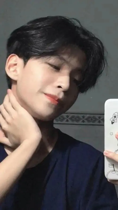 Chàng trai có gương mặt thanh tú nghiêng đầu nhìn sang một bên trong chiếc áo thun màu xanh đen đơn giản tôn lên làn da trắng và sống mũi cao