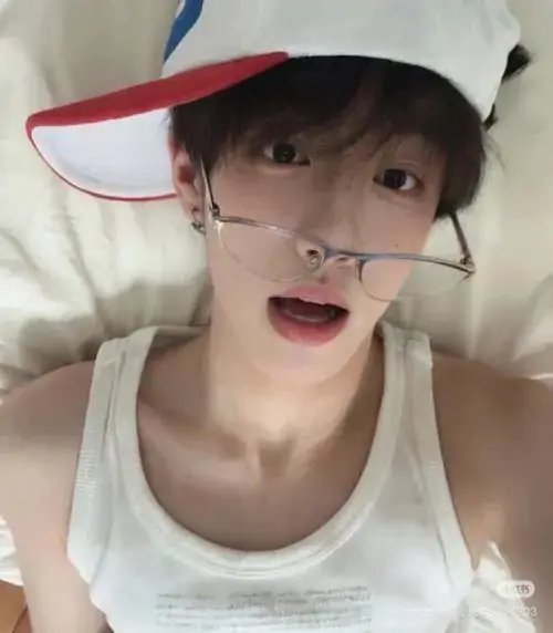 Góc chụp selfie cận mặt thể hiện nét trẻ trung của một trai đẹp đội mũ lưỡi trai ngược kết hợp kính mắt tròn và chiếc áo ba lỗ trắng năng động