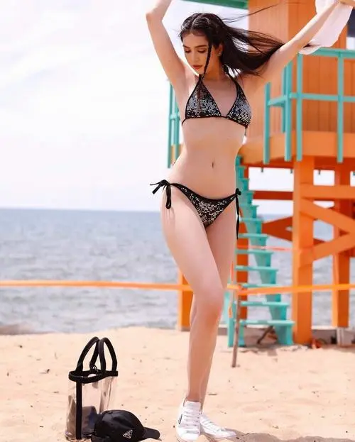 Tạo dáng bãi biển trong bikini trắng đem lại cảm giác trong trẻo, người mẫu đưa tay chỉnh tóc và nhìn xuống rất nhẹ nhàng