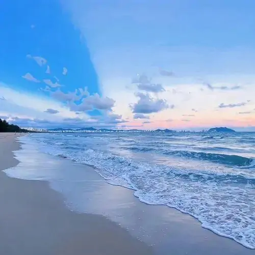 Bãi cát mịn màng đón từng đợt sóng nhỏ dịu dàng xô bờ dưới nền trời chuyển màu hồng lam dịu mát lúc chiều tà buông xuống không gian